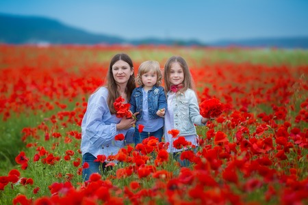 beautiful young woman with child girl in poppy field. happy family having fun in nature. outdoor portrait in poppies. mother with daughter. summer time.の写真素材
