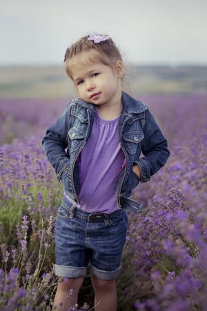 Beautifull cute blond Young beauty girl in blue jeans and purple shirt posing to camera with cosy smile face.Wellbeing time spending in village fields of lavender in august France Provence.の写真素材