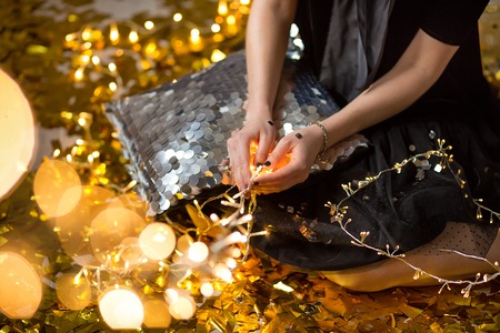 Amazing cute lady celebrating new year birthday party, posing in gold shine background and throwing...