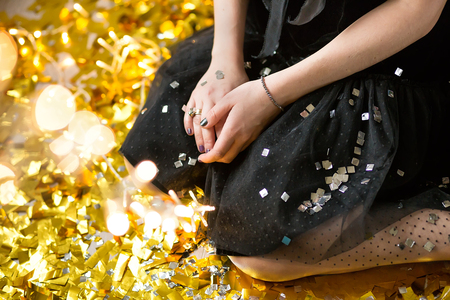 Amazing cute lady celebrating new year birthday party, posing in gold shine background and throwing colorful confetti with silver baloonsの写真素材