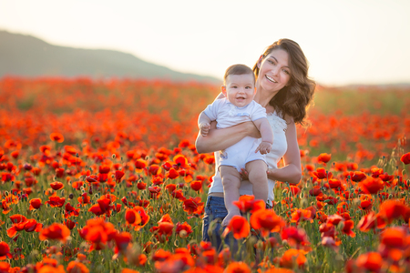 Outdoor portrait. Young mother and her daughter enjoy life time together on a poppy field . Concept of love and happy family. Poppy meadow.の写真素材