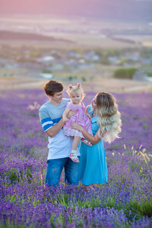 Happy family of father mother and daughter enjoy vacation on field of lavender flowers. Sensual scene of family happynessの写真素材