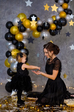 Woman power party with beautiful model mother and cute baby daughter dressed in airy black fancy dresses celebrating love with golden stars and air baloons. Pillow stars SUPER STAR designed by photographerの写真素材