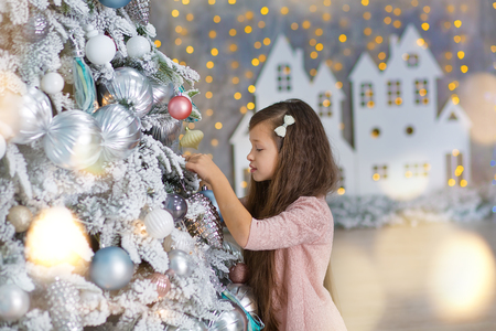 Cute girl near the Christmas tree enjoy miracle winter time. Christmas concept. Belief in miraclesの写真素材