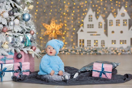 Christmas portrait of cute little newborn baby boy, dressed in christmas clothes and wearing santa hat, studio shot, winter time.の写真素材
