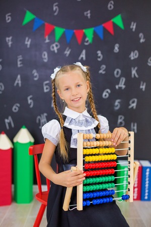 The schoolgirl in school uniform with books and textbooks is on a light gray background. Back to school. The new school year. Child education conceptの写真素材
