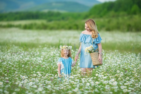 Happy mother and daughter child together with yellow dandelion flowers in summer dayの写真素材