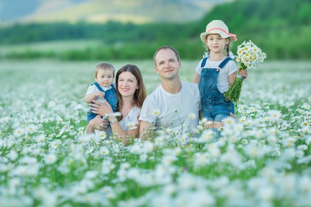 Young family in a field of flowers daises chamomile anjoy spa life happy together with cute faces in a village rustic motion.の写真素材