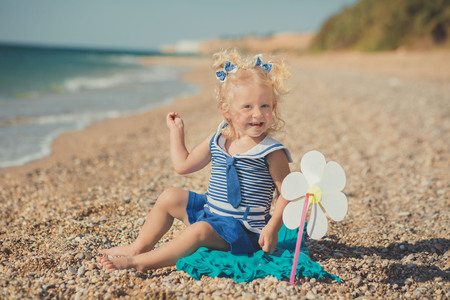 Cute girl on a sea side with two sea stars in blue dressの写真素材