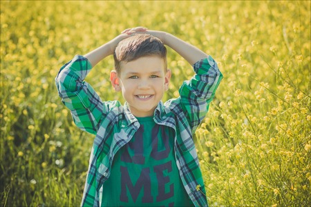 Handsome boy with blond hair in canola field.