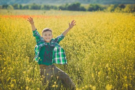Handsome boy with blond hair in canola field.