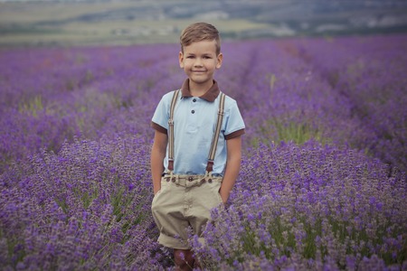 Cute little boy with on lavender field on beautiful summer day stylish dressed.の写真素材