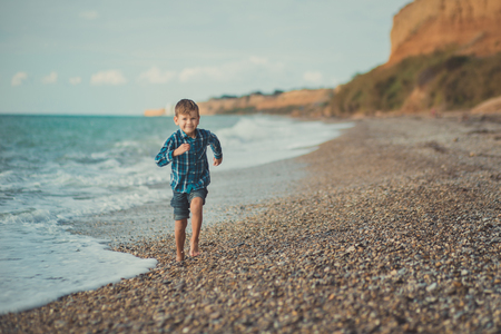 Portrait of happy boy running alone at beach.の写真素材