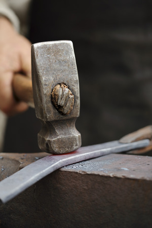 Detail shot of hammer forging hot iron at anvilの写真素材