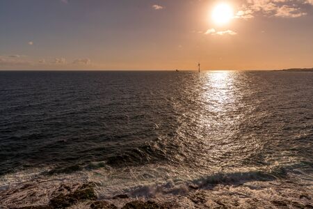 Sunrise from a cliff with moving clouds in a different direction forming a line where the sun rises on the sea and forms rays reflecting on the ocean surface from the Grand Canary.の写真素材
