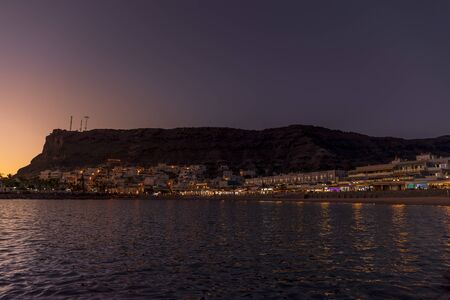 Sunset passing behind the horizon behind buildings view from beach to part of the city with...