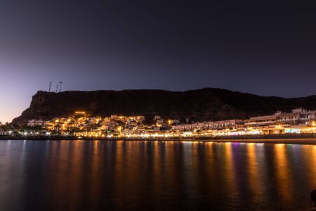 Mogan beach during sunset with the city lit up by street lights and freshly lit streets of the grand canary island valleyの写真素材