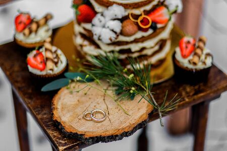 Wedding cake with fruit and an old wooden table with needles of cones and leaves during a wedding ceremony in winter on snow in the middle of a forest covered with fresh snowの写真素材