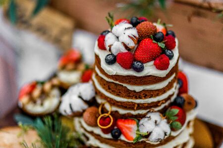 Wedding cake with fruit and an old wooden table with needles of cones and leaves during a wedding ceremony in winter on snow in the middle of a forest covered with fresh snowの写真素材