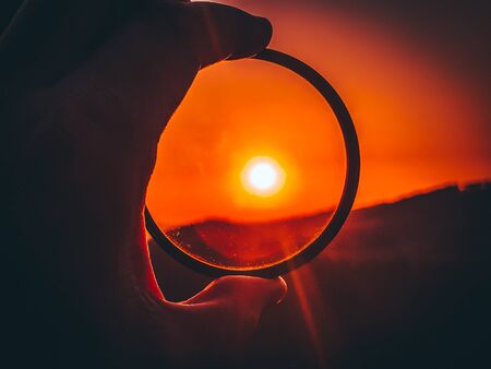 Taking photos of sunset through the camera filter inside nature.の写真素材