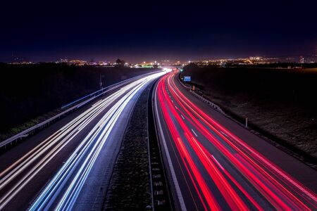 Highway light car trails leading from passing cars during night.