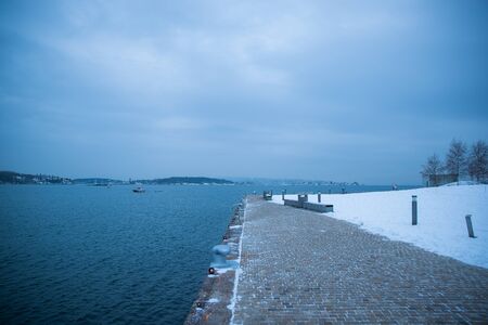 Oslo Norway coast during winter with a large number of docked boats in the center of the city covered with snowの写真素材