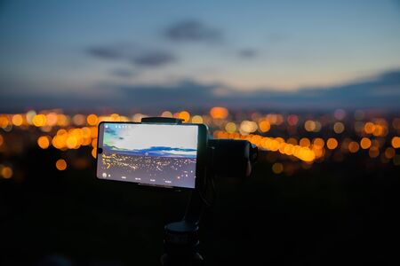 Mobile phone taking pictures on colorful sunset on Bila Hora with amazing view on city Brno Czech...