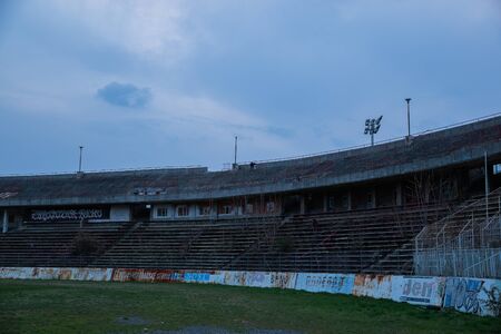Abadoned Stadion Za LuÅ¾Ã¡nkami is a currently inactive stadium in Brno, Czech Republic. Captured in spring sunset, sky and clouds was colored to blue dark colors. Photo from tribunes and inside middle of field.の写真素材