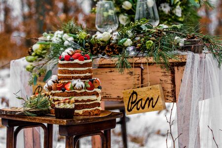 Wedding cake with fruit and an old wooden table with needles of cones and leaves during a wedding...
