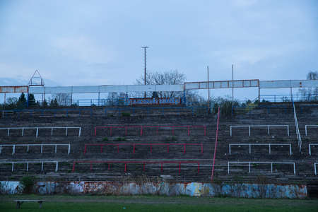 Abadoned Stadion Za LuÅ¾Ã¡nkami is a currently inactive stadium in Brno, Czech Republic. Captured in spring sunset, sky and clouds was colored to blue dark colors. Photo from tribunes and inside middle of field.のeditorial素材