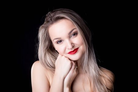 Close up studio portrait of a pretty blonde woman, smiling with red lips and looking at the camera, against plain studio backgroundの写真素材