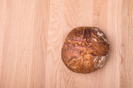 Round loaf of freshly backed sourdough bread on wooden tableの写真素材