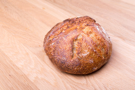 Round loaf of freshly backed sourdough bread on wooden tableの写真素材