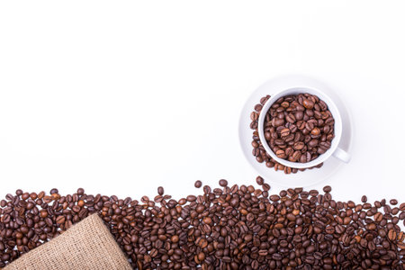 top view of White cup filled with freshly roasted coffee beans isolated on white backgroundの写真素材