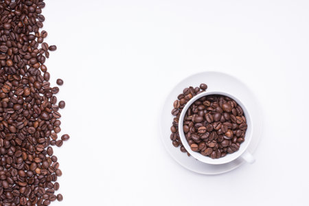 top view of White cup filled with freshly roasted coffee beans isolated on white backgroundの写真素材