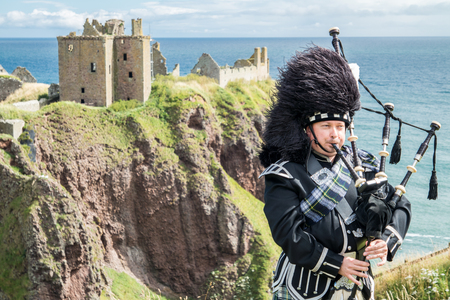 Traditional Scottish bagpiper in full dresscode at Dunnottar Castle in Stonehavenの写真素材