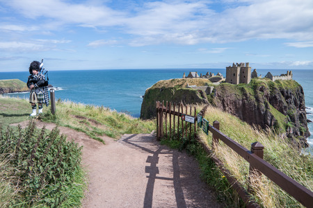 Traditional Scottish bagpiper in full dresscode at Dunnottar Castle in Stonehavenの写真素材