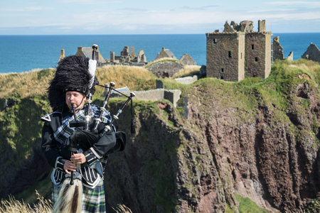 Traditional Scottish bagpiper in full dresscode at Dunnottar Castle in Stonehavenの写真素材
