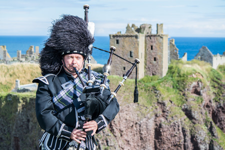 Traditional Scottish bagpiper in full dresscode at Dunnottar Castle in Stonehavenの写真素材