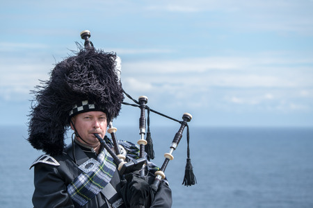 Traditional Scottish bagpiper in full dresscode at Dunnottar Castle in Stonehavenの写真素材