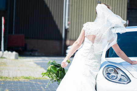 Bride in Wedding Dress going on the honeymoon with carの写真素材