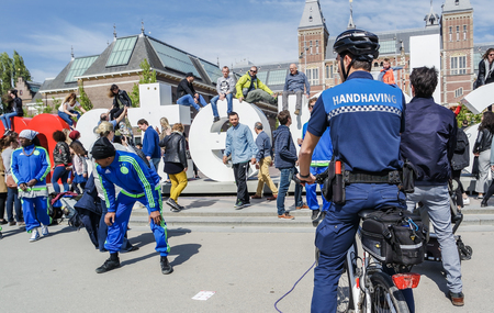 Amsterdam / Netherlands - April 31, 2017 : The handhaving police department having a look an the street performancesのeditorial素材