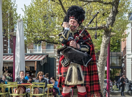 Amsterdam / Netherlands - April 31, 2017 : Scottish bagpiper tuning his instrument in the streets of Amsterdam wearing his Royal Stuart tartanのeditorial素材