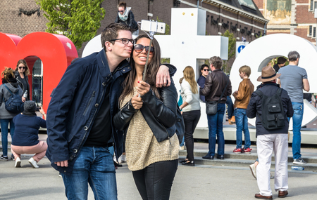 Amsterdam / Netherlands - April 31, 2017 : Couple taking selfies while people walking around the I Amsterdam letters in the square in front of the museum, time lapseのeditorial素材
