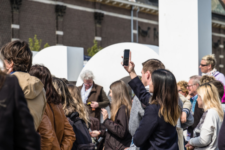 Amsterdam / Netherlands - April 31, 2017 : Asian lady taking selfies while people walking around in the streetsのeditorial素材