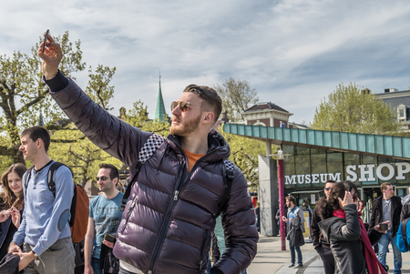 Amsterdam / Netherlands - April 31, 2017 : Man taking selfies while people walking around in the streetsのeditorial素材