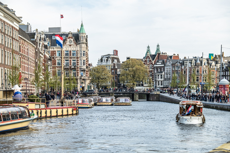 Amsterdam / Netherlands - April 31, 2017 : Boats driving on the canals of Amterdam while sightseeing vessels are waiting for guestsのeditorial素材