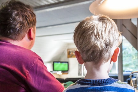 Father and son watching TV at home together