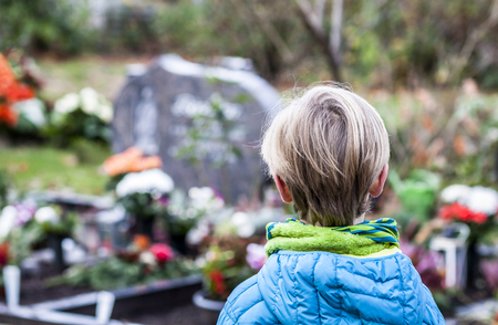 Little boy standing at the grave of his parentsの写真素材