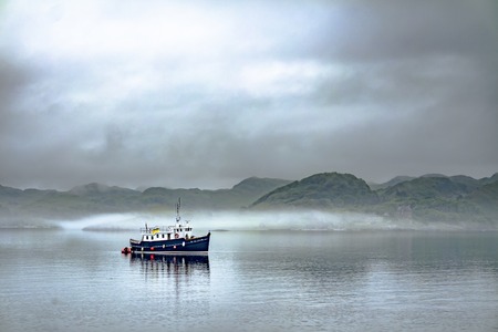 Alone boat driving through in the foggy sea in the scottish highlands